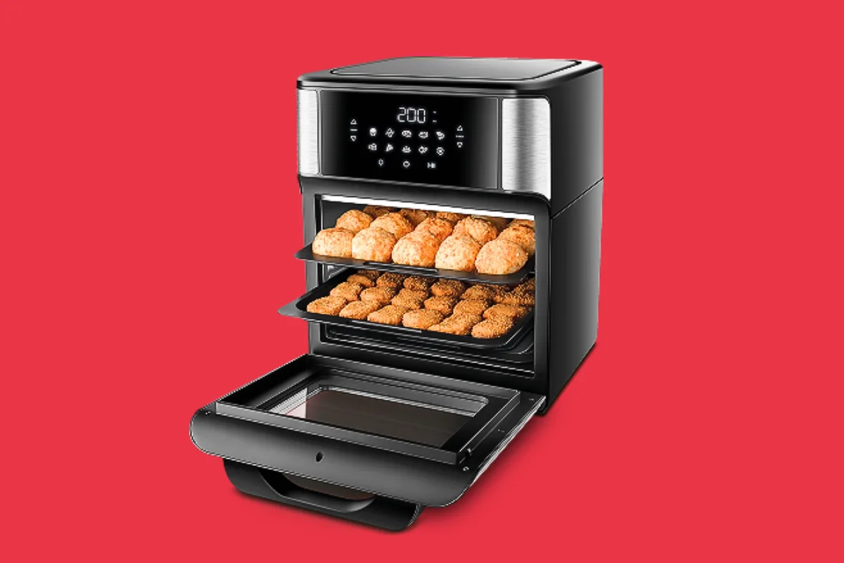 Mão posicionando uma forma de silicone vermelha com furos dentro do cesto aberto de uma fritadeira air fryer sobre uma bancada limpa